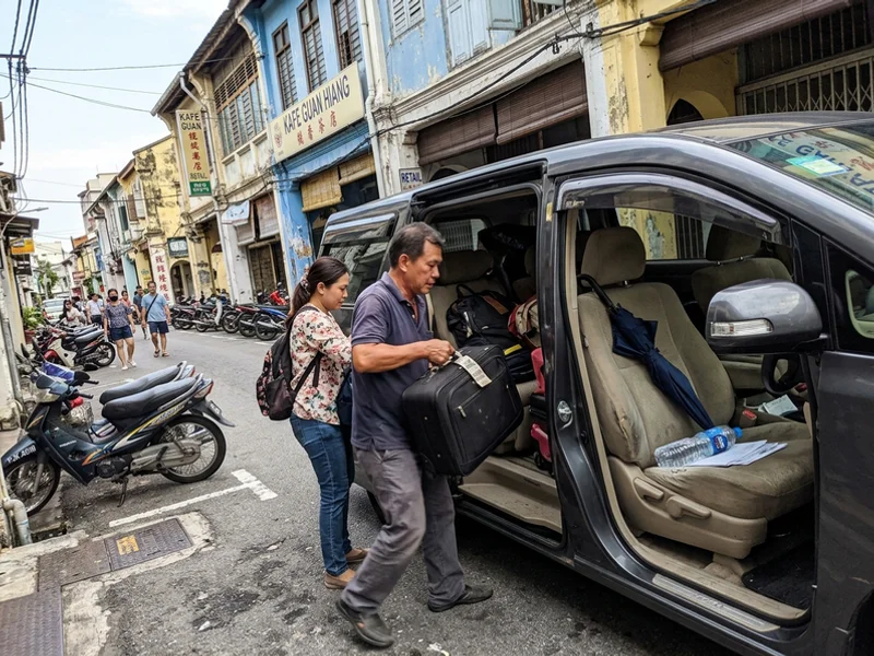 An air-conditioned MPV with its door open as bags are loaded