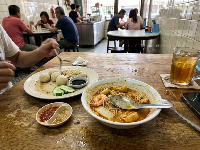 Chicken rice balls and Nyonya laksa mid-meal on a cafe table
