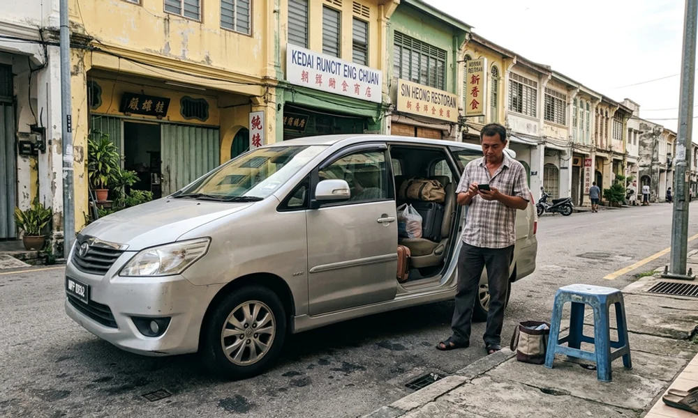 An air-conditioned MPV waiting on a quiet street with the sliding door open, bags half-loaded