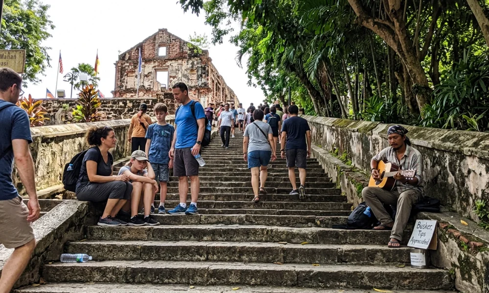 Visitors walking up the steps toward the ruined church on St Paul's Hill in Malacca in ordinary daylight