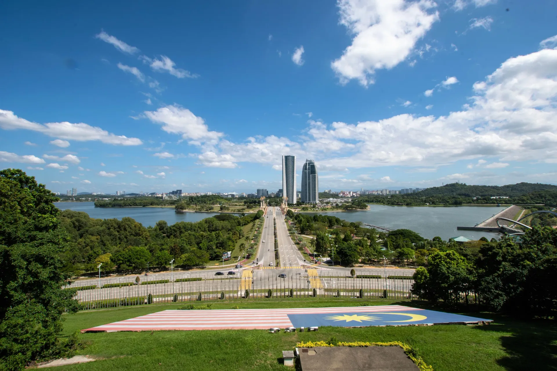 Putrajaya's lake and central boulevard seen from the hill, with a Malaysian flag laid out on the grass